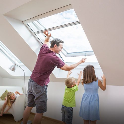 Vater öffnet mit seinen Kinder ein Rollo für Dachfenster