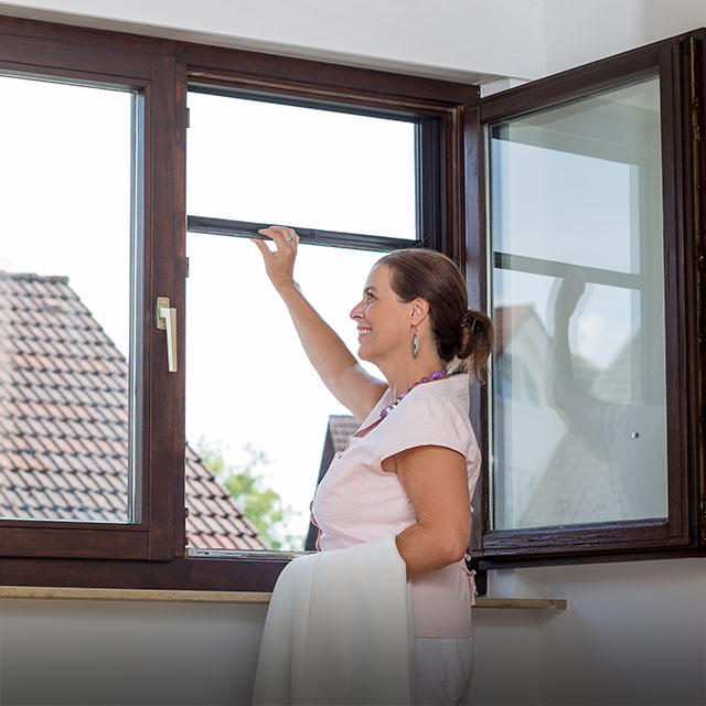 Woman opens insect screening roller screen on window