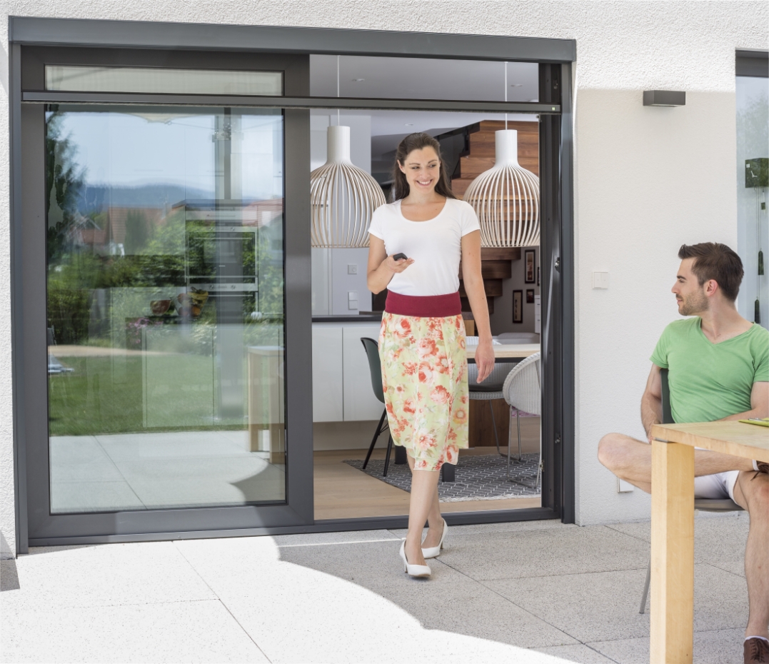 Neher Elektrorollo an Tür oder Fenster, Bedienung per Knopfdruck; schlanke Kassette, leiser Motorlauf und präzise Führungsschienen für Insektenschutz.