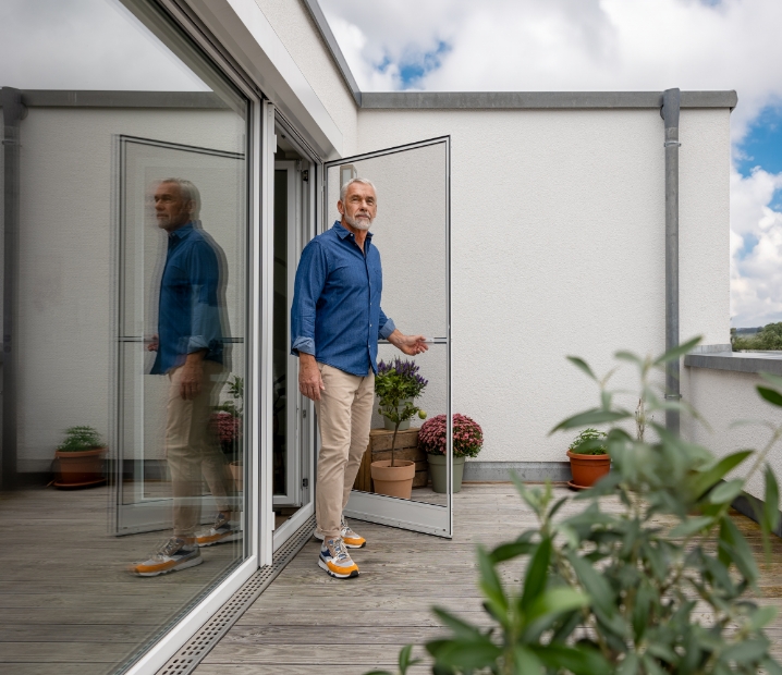 Neher Insektenschutz-Drehtür wird von einem Mann geöffnet um auf den Balkon zu kommen.