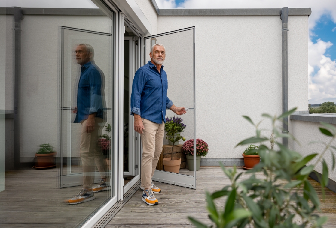 Person geht durch Insektenschutz Drehtür auf den Balkon.