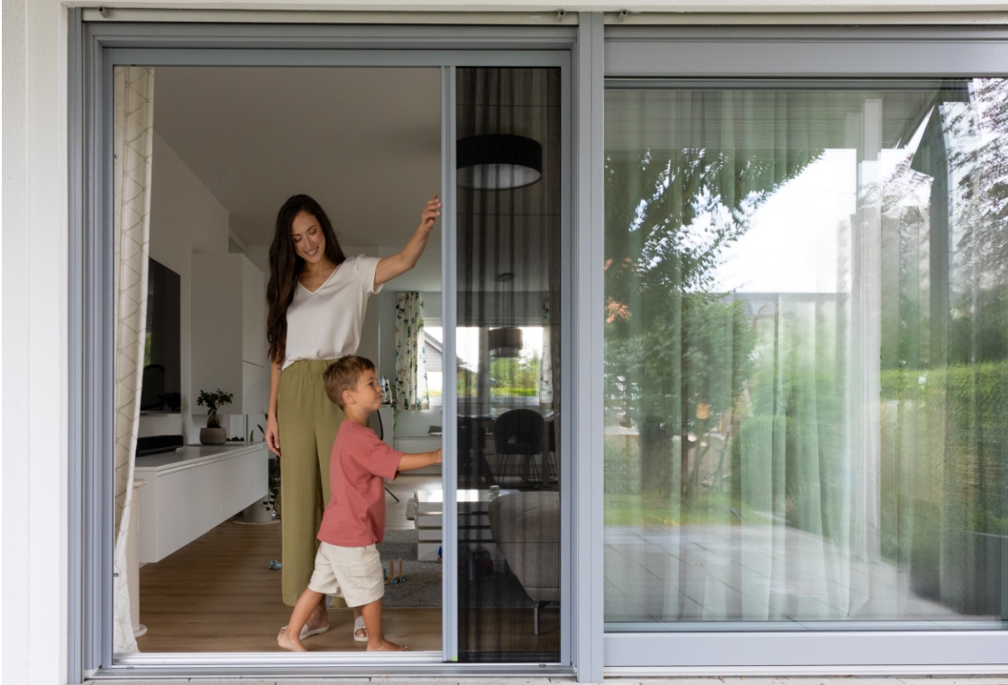 Person schiebt ein Neher Insektenschutz‑Plissee leichtgängig zur Seite.