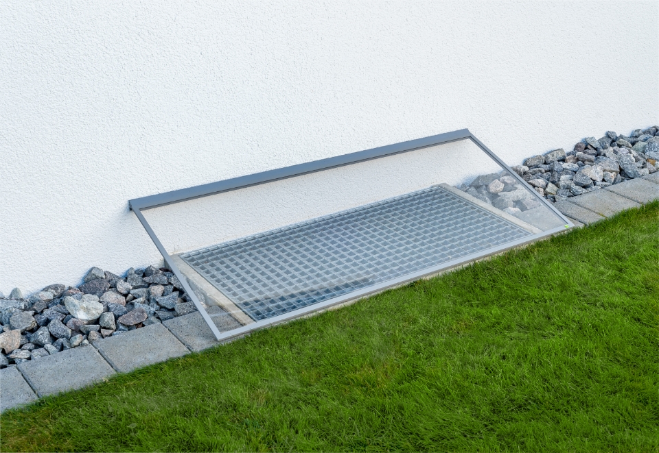 RESi regensichere Lichtschachtabdeckung mit transparenter, schräger Abdeckung an der Hauswand.