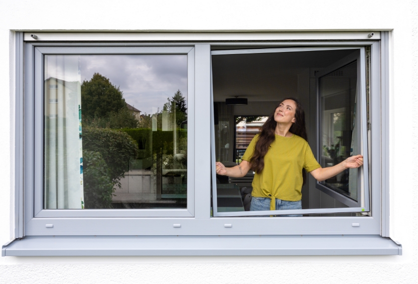 Person bedient Insektenschutz Spannrahmen. Einfache Montage eines Fliegengitter Spannrahmens am Fenster. Ohne Bohren oder Kleben.