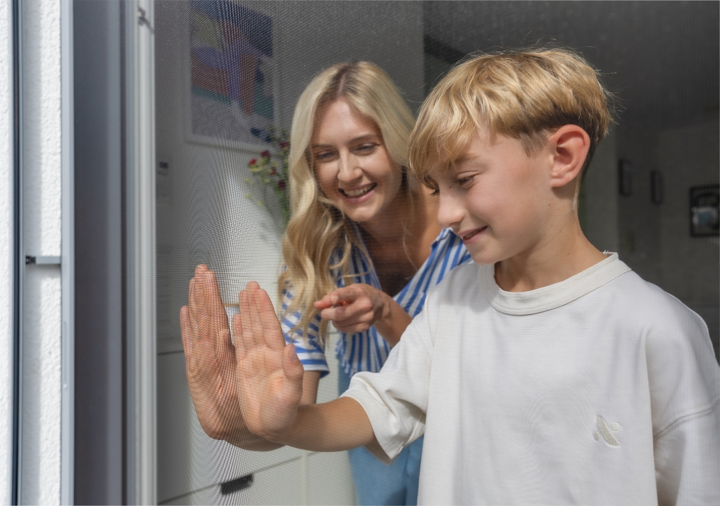 Kind und Frau betrachten das Insektenschutzgewebe an einer Tür