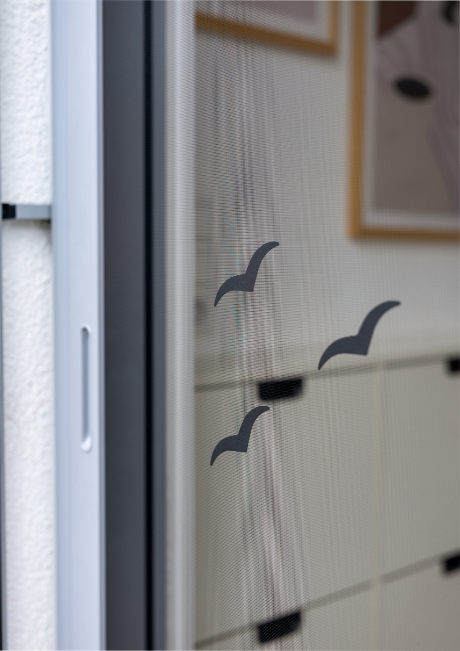 Insektenschutz-Schiebetür mit Durchlaufschutz durch drei Vogel-Aufkleber auf dem Gewebe.